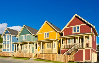 Four neighboring homes, the first blue, then green, yellow, and red.