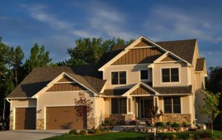 A home with several types of siding: rock, shingles, and vertical siding.