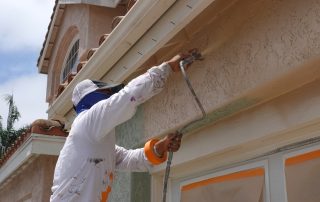 painter painting the stucco exterior of a home