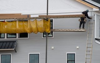 A man installs fiber cement siding onto a home exterior.