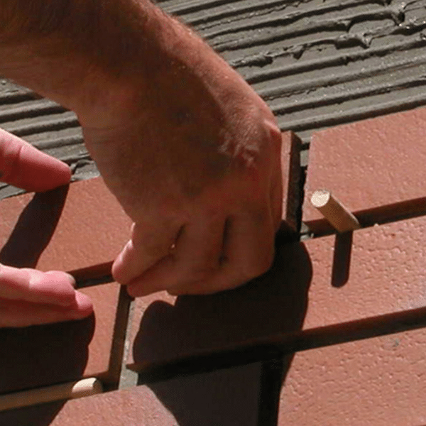 Happy Homeowners After Exterior Brick Remodel Homeowners reviewing exterior renovation plans with a contractor in front of their updated brick home