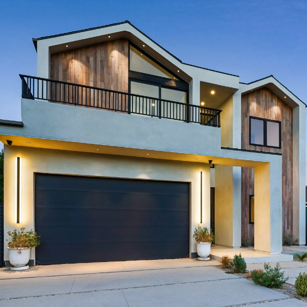 Modern two-story house in Salt Lake City with large black garage door, clean lines, expert stucco installation, wood and stucco exterior, balcony, outdoor lighting, and potted plants at the entrance. Modern two-story house in Salt Lake City with large black garage door, clean lines, expert stucco installation, wood and stucco exterior, balcony, outdoor lighting, and potted plants at the entrance.