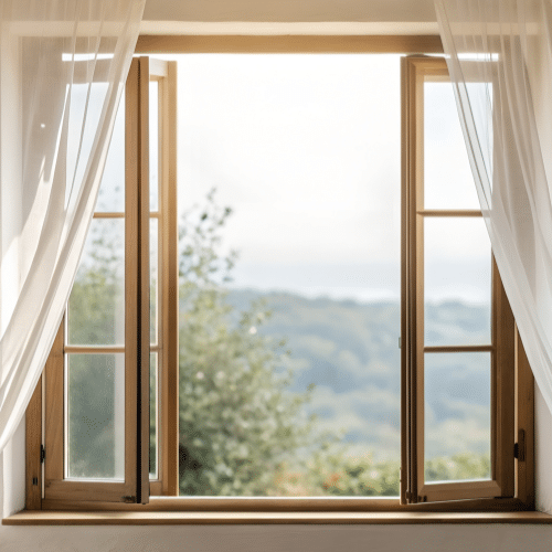 An open wooden-framed window with sheer white curtains reveals a blurred view of green trees and a hazy sky—typical scenery after a composite window installation in Salt Lake City, Utah. An open wooden-framed window with sheer white curtains reveals a blurred view of green trees and a hazy sky—typical scenery after a composite window installation in Salt Lake City, Utah.